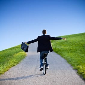 Businessman on unicycle cropped